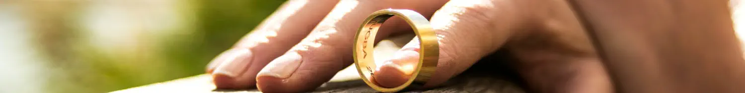 Closeup of the hand of a woman who has taken off her wedding ring and is balancing it with one finger