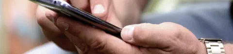 Closeup of a man holding his mobile phone and touching the screen