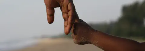 Closeup of the hands of an adult and child holding hands